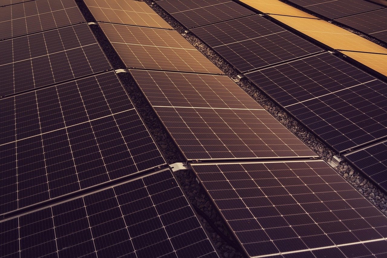 Flach aufgeständerte Solarmodule in Reihen auf einem mit Kies bedeckten Flachdach